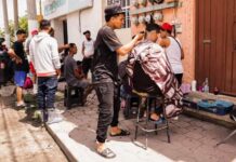 Jóvenes venezolanos instalan su «barbería» en la banqueta de su calle.