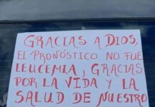 Madre celebra con un cartel en su auto que su hijo no padece leucemia.